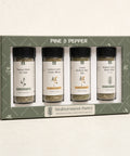 A boxed spice set labeled PINE & PEPPER, containing four glass spice jars with black lids and white labels: Tuscan Herb Sea Salt, Lemon Grass Garlic Blend, Greek Herb & Sin Mix, and Italian Garum Herb Blend. The set is presented in a muted green gift box with Mediterranean Pantry branding, photographed on a clean off-white background.